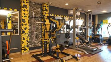A gym with various exercise equipment, a mirror, and a stone wall.