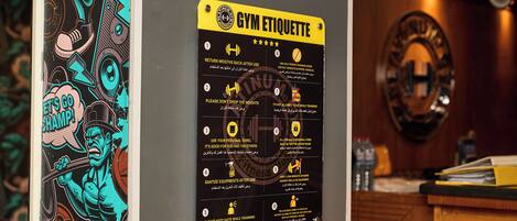 A gym etiquette poster on a wall with a mirror and a wooden counter.