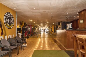 A gym with a reception desk, exercise equipment, and a mirrored wall. - The Fit Stop Hostel (Hurghada)