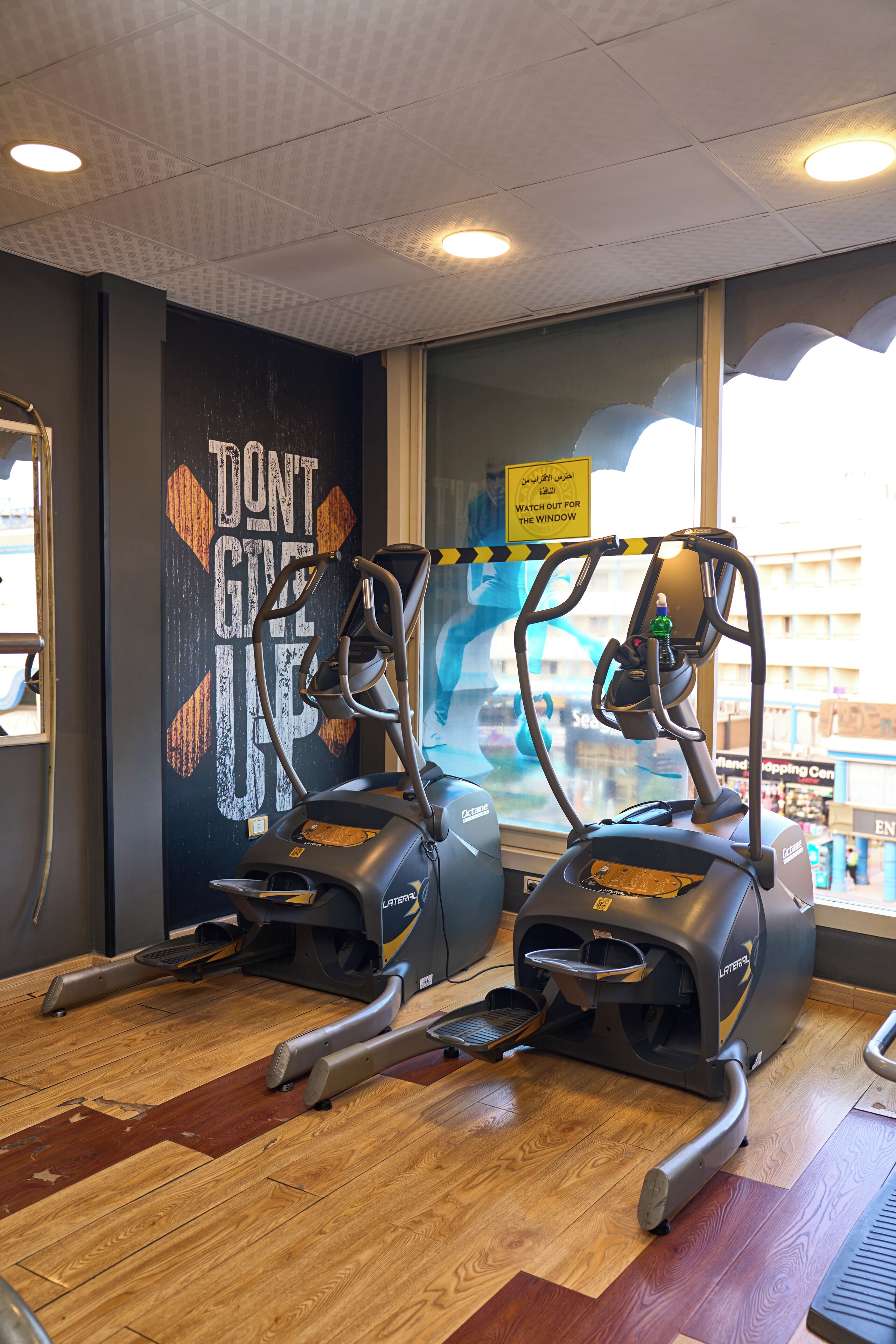 Une salle de sport intérieure équipée de deux tapis de course, d’une affiche motivante et d’une fenêtre donnant sur l’extérieur.