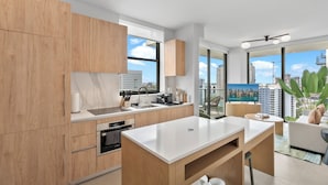 Eine moderne Küche mit Holzausstattung, einer weißen Arbeitsplatte und einem großen Fenster mit Blick auf die Stadt.