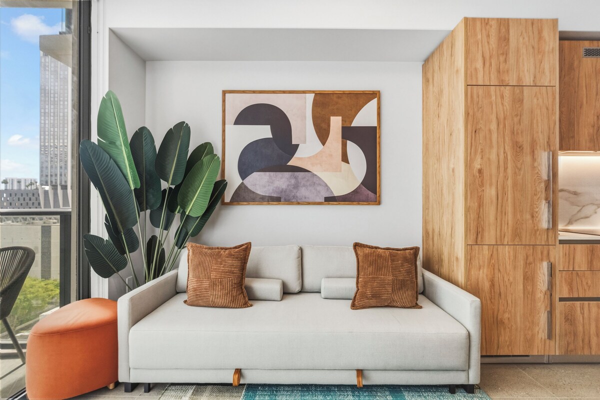 Ein modernes Wohnzimmer mit einer Couch, Kissen, einem großen abstrakten Gemälde und einer Holztruhe.