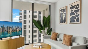 Ein modernes Wohnzimmer mit Sofa, Couchtisch und Fernseher, der eine Stadtansicht zeigt.