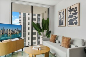 A modern living room with a sofa, coffee table, and a TV displaying a cityscape. - Miami Luxury Condo (Miami)