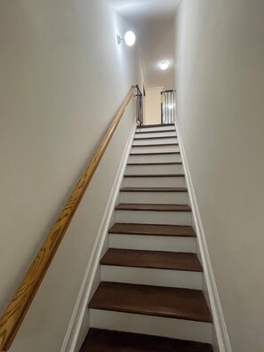 A staircase with wooden handrails and white walls.