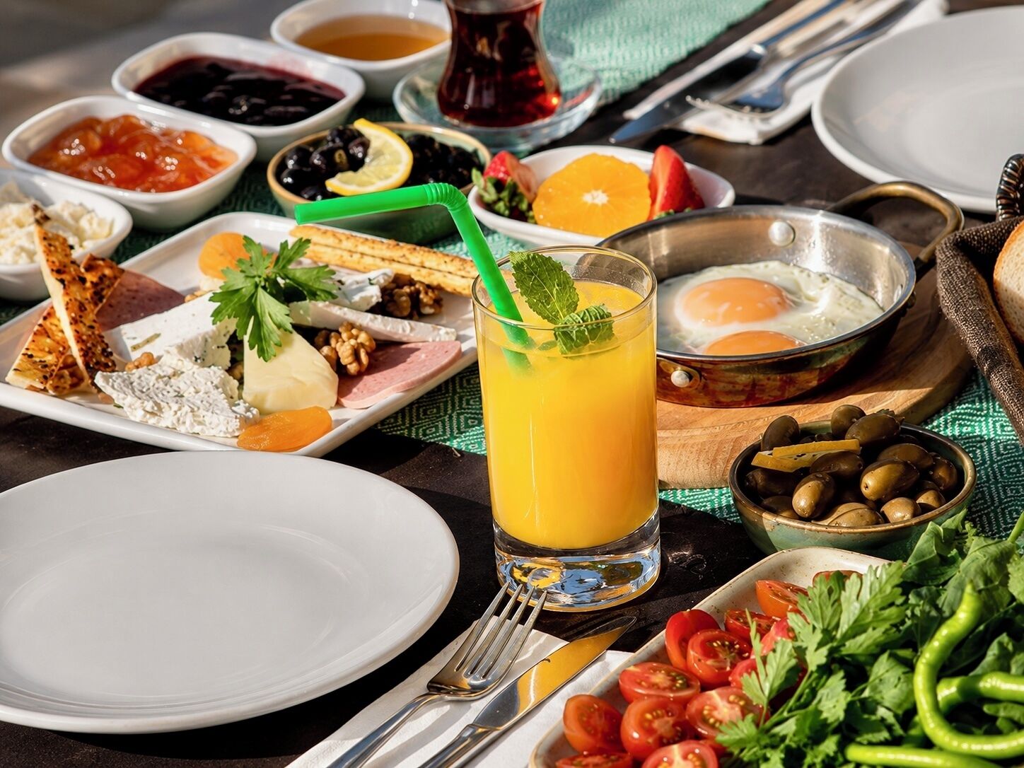 A breakfast setting with various food items and a glass of orange juice.