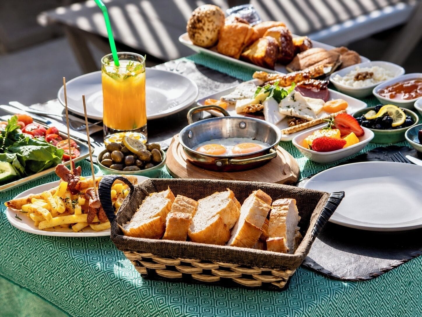 A table set with a variety of breakfast items including bread, eggs, fruits, and a beverage.