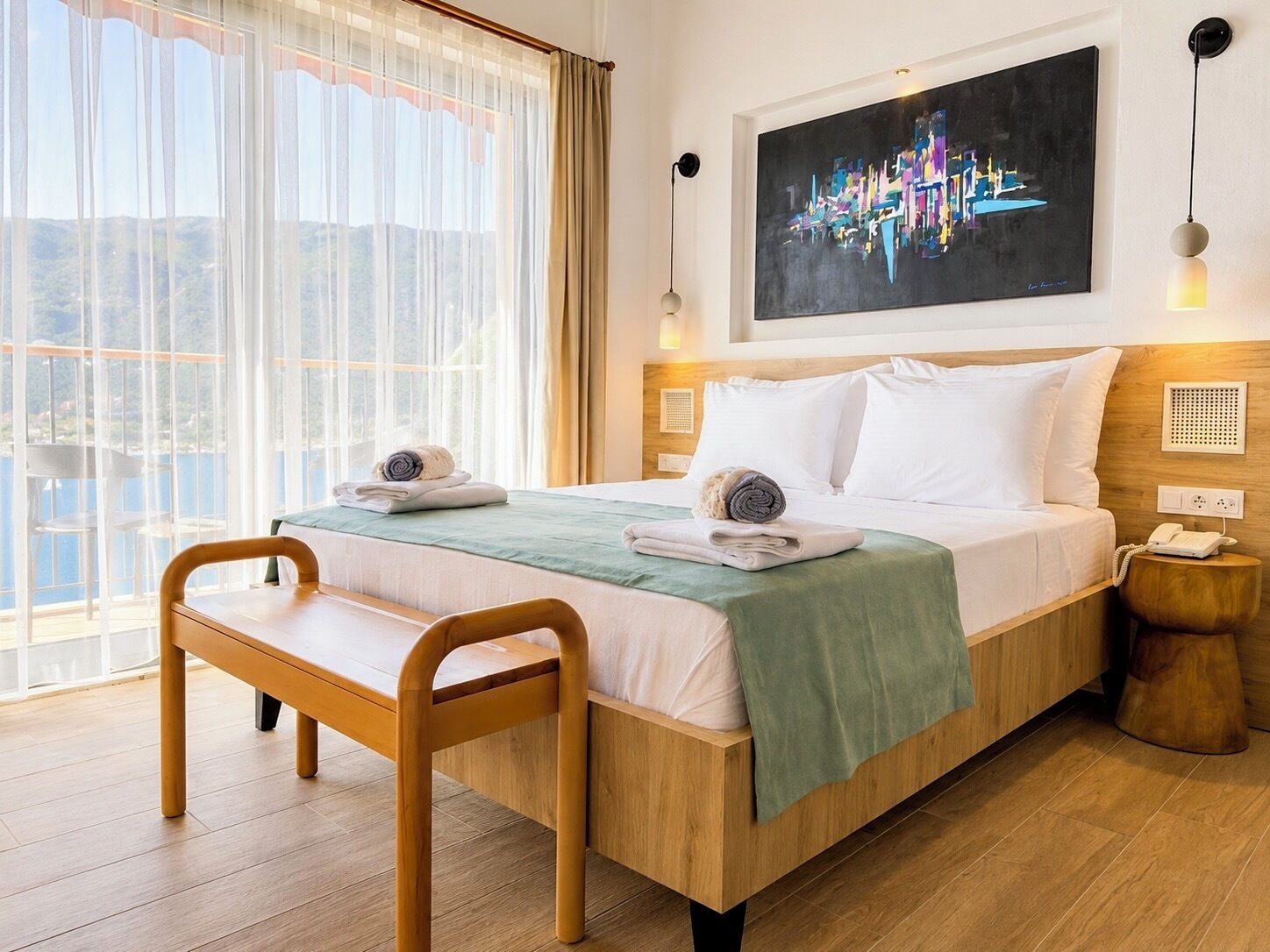 Hotelkamer met een bed, een bureau en een stoel. Er is een raam met gordijnen, een schilderij aan de muur en een telefoon op het nachtkastje.