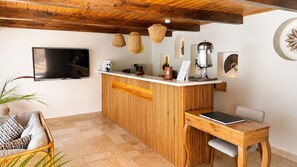 A modern kitchen with a wooden bar, a flat-screen TV, and a dining area with a table and chairs.
