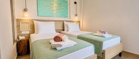 A hotel room with two beds, a painting, an air conditioner, a bedside telephone, and a small table.
