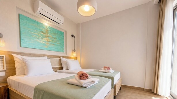 A hotel room with two beds, a painting on the wall, an air conditioning unit, and a window with curtains. - Adasya Hotel (Kas)