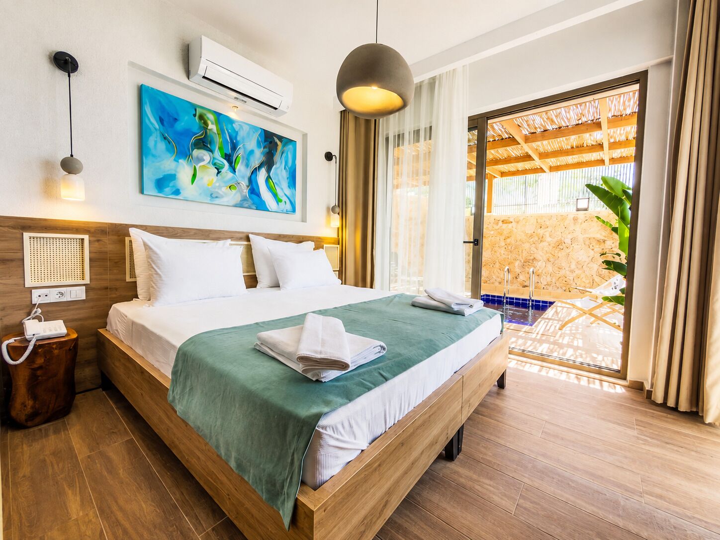 Une chambre d’hôtel comprenant un lit, un tableau, un appareil de climatisation, un téléphone sur la table de chevet et donnant sur un espace extérieur.