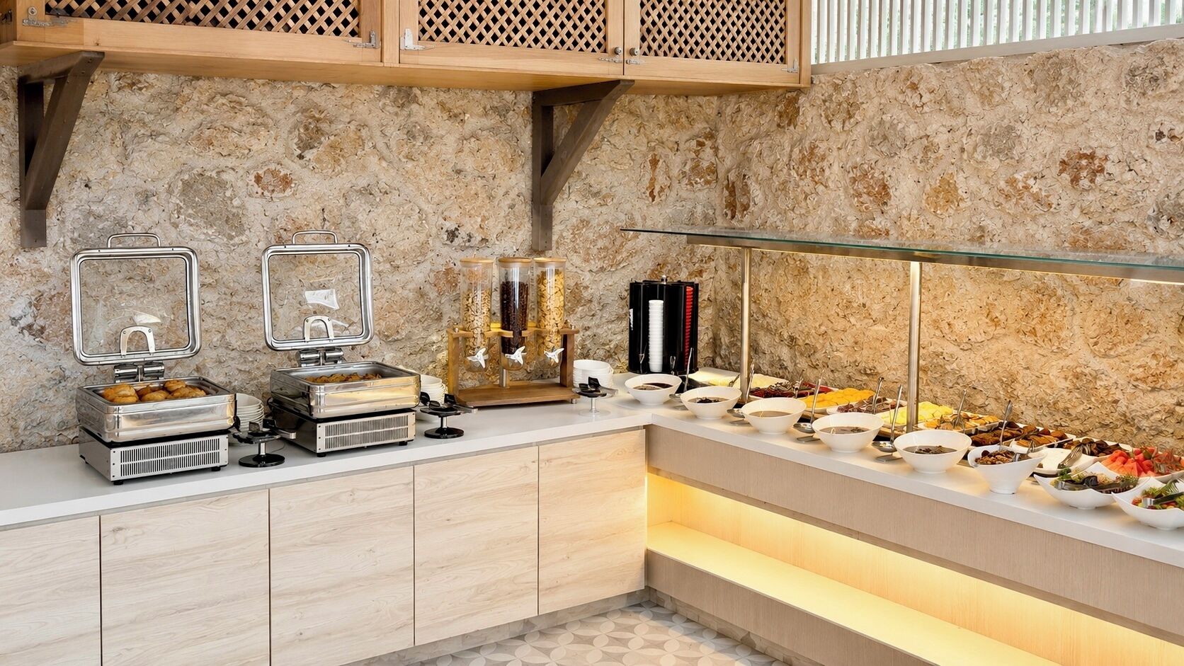 A buffet setup with various food stations, including a grill, a fruit display, and a beverage dispenser.