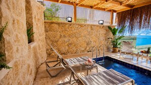 A poolside area with lounge chairs and a small pool, surrounded by stone walls and a wooden pergola. - Adasya Hotel (Kas)
