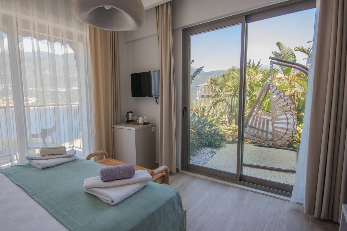 Habitación de hotel con cama, escritorio, televisión y balcón con vistas al exterior.
