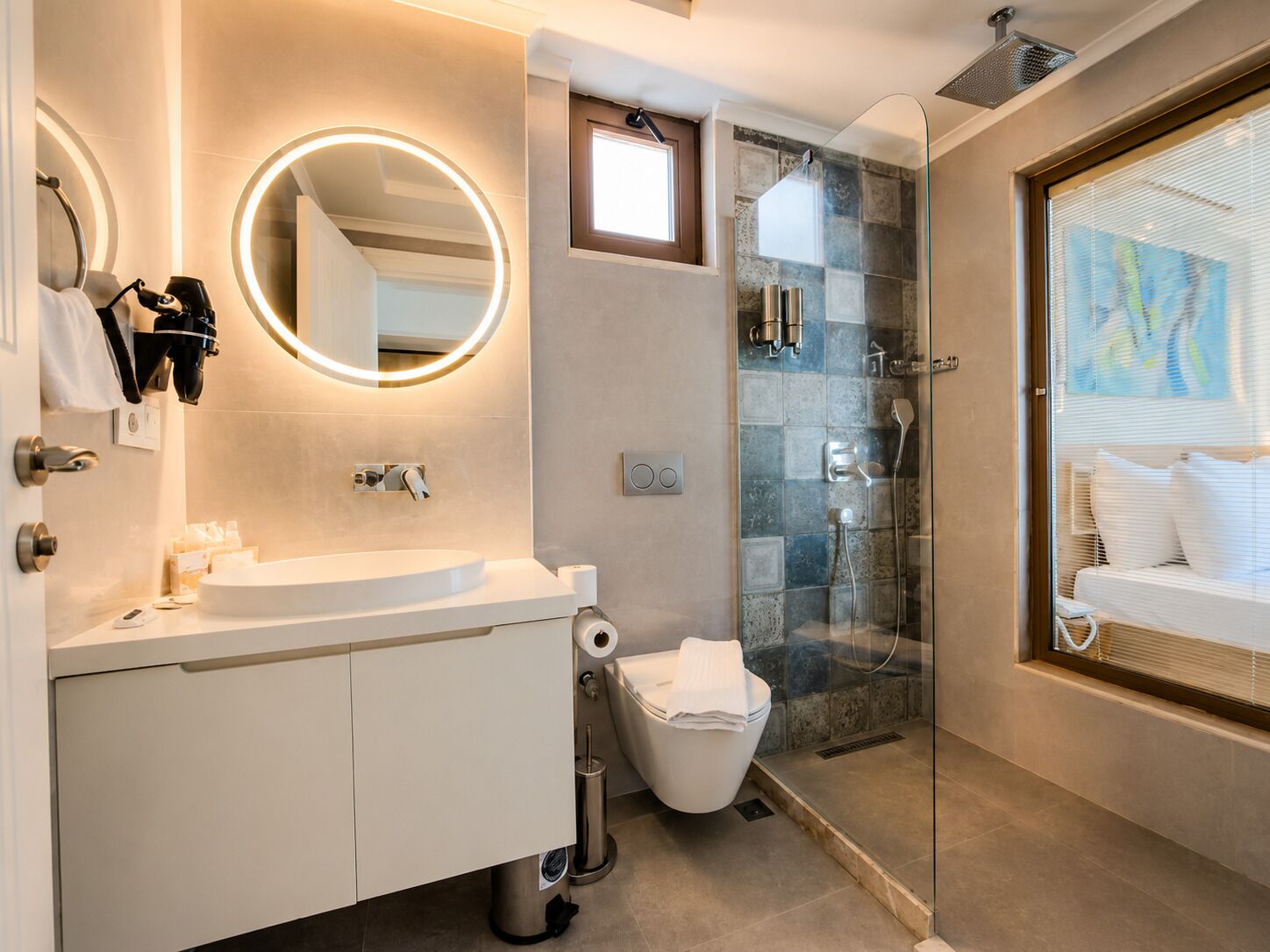 A modern bathroom with a round mirror, a toilet, and a shower area.