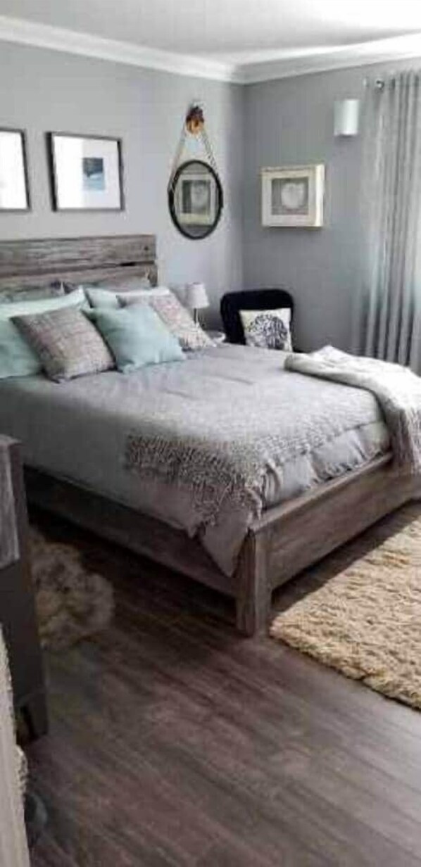 A bedroom with a large bed, a wooden headboard, a rug, and framed pictures on the wall.