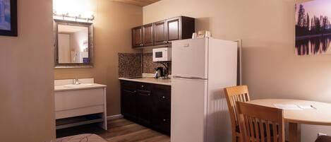 A compact kitchen with a refrigerator, microwave, and wooden cabinets.