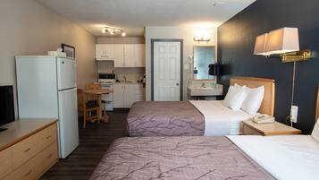 Habitación de hotel con dos camas, un escritorio, refrigerador, microondas, lavamanos y espejo.