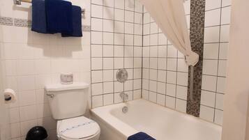 A bathroom with a toilet, bathtub, shower curtain, and a towel rack with two towels.