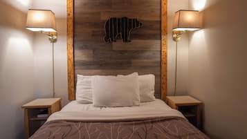 Un dormitorio con una cama, dos mesitas de noche, un cabecero de madera con silueta de oso y dos lámparas de pared.