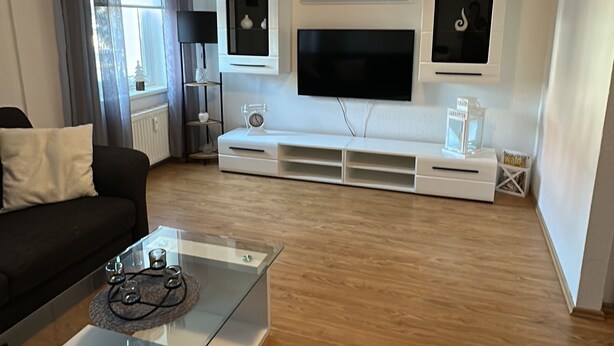 A modern living room with a flat-screen TV, a coffee table, and a sofa. - FAMILY-FRIENDLY VACATION APARTMENT IN THE CENTER OF BRAUNLAGE (Braunlage)