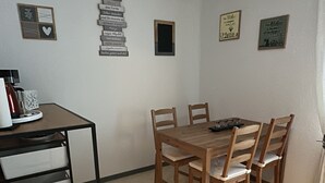 A dining area with a wooden table and chairs, a small window, and wall decorations. - FAMILY-FRIENDLY VACATION APARTMENT IN THE CENTER OF BRAUNLAGE (Braunlage)
