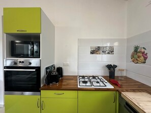 Una cucina con microonde, forno, tostapane e piano cottura a gas.