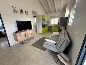 Ein modernes Wohnzimmer mit Flachbildfernseher, grauem Sofa und einer Holzkabine.