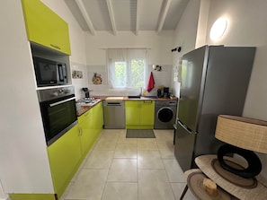 Uma cozinha compacta com micro-ondas, forno, lava-louças e geladeira.
