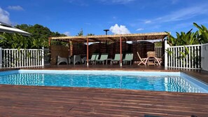 Piscina com espreguiçadeiras e área de estar coberta.
