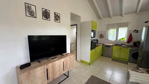 Eine moderne Küche mit Fernseher, ein Essbereich mit einer Couch und ein Wohnzimmer ebenfalls mit einem Fernseher.