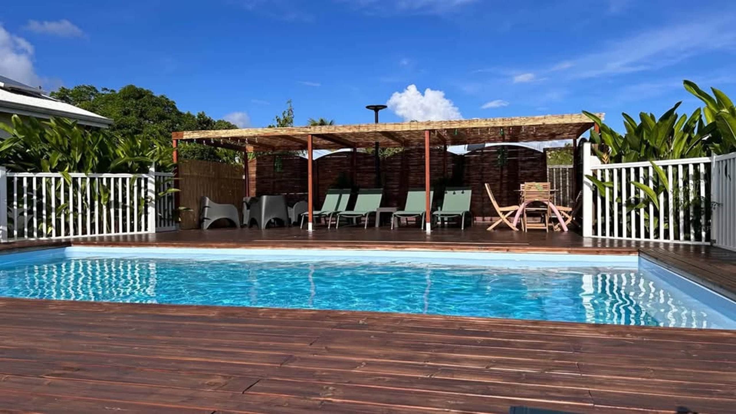 Una piscina con sillas de descanso y una zona de estar cubierta.