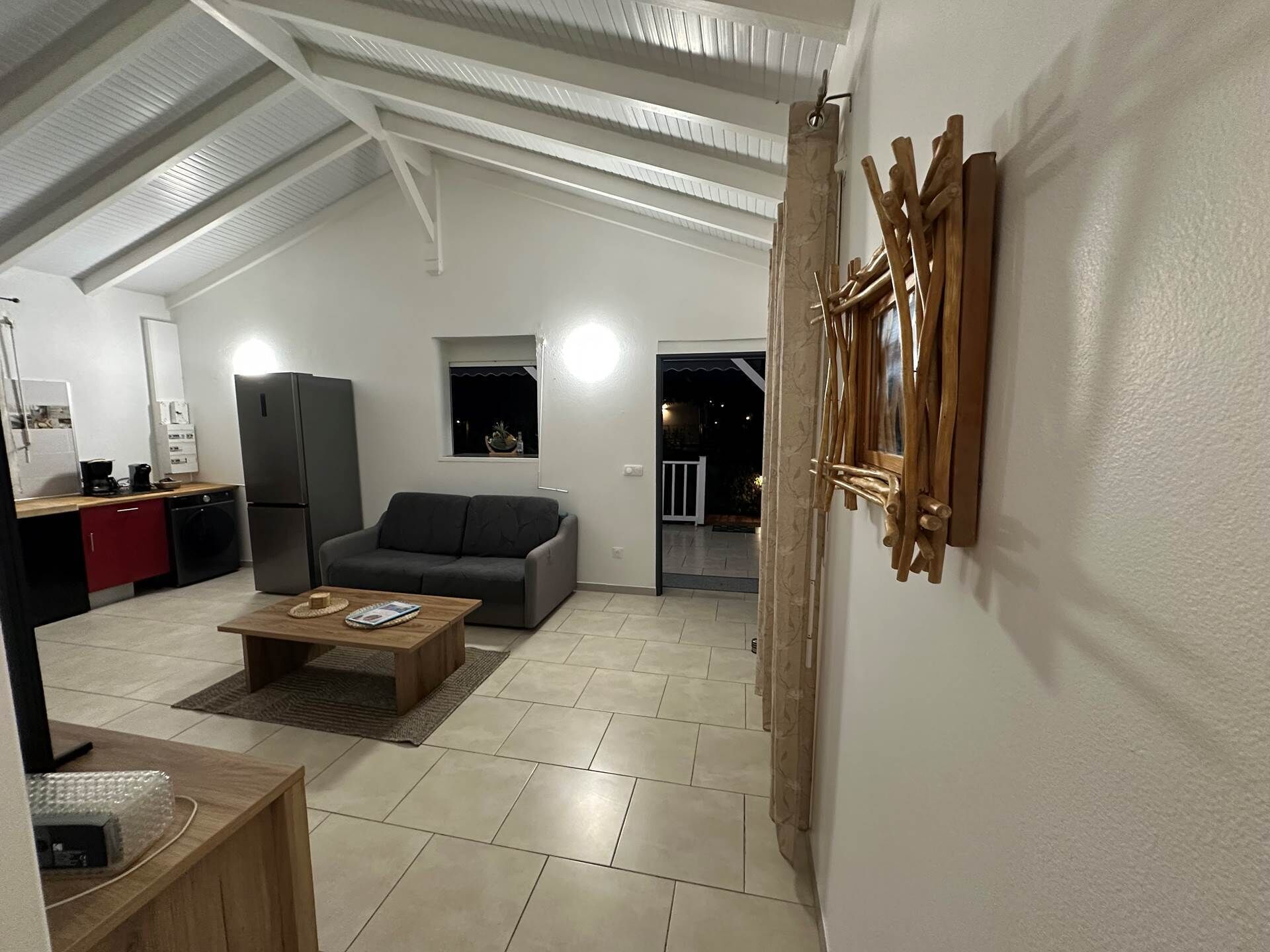 Un intérieur moderne comprenant une cuisine, un canapé gris, une table basse en bois et un coin repas.