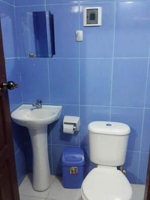 A bathroom with a sink, toilet, and trash bin. - Hotel Aguilar (Uyuni)