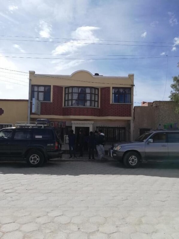 A two-story building with a flat roof and a central entrance. - Hotel Aguilar (Uyuni)