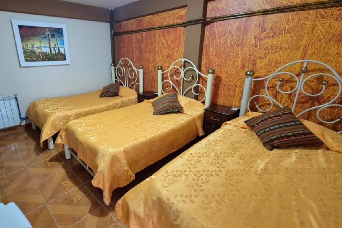 A hotel room with three beds, each with a patterned bedspread and matching pillows.