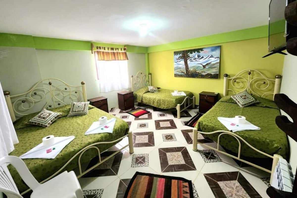 A hotel room with two beds, a small desk, a chair, and a painting on the wall.