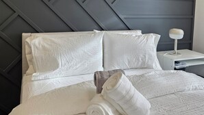 A neatly made bed with white linens and pillows, a modern headboard with a geometric pattern, and a bedside table with a lamp. - Pakallen De-Paris Ensuite Master Bdrm 5 min to UofA, UofA Hospital. Free wifi (Edmonton)