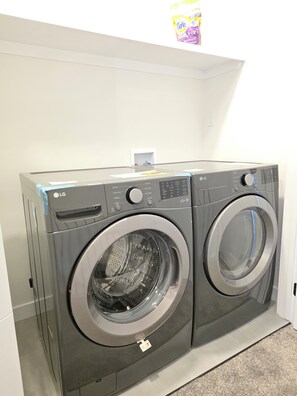 Eine Frontlader-Wasch- und Trockner-Kombination von LG mit Bedienfeld, Waschmittelschublade und Sicherheitshinweis.