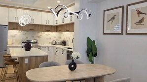 A modern kitchen with white cabinets, a central island, and a hanging light fixture. - Pakallen De-Paris Ensuite Master Bdrm 5 min to UofA, UofA Hospital. Free wifi (Edmonton)
