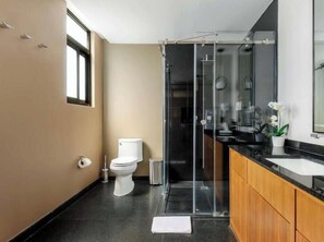 Une salle de bain moderne équipée de toilettes, d’une douche et d’un meuble-lavabo.