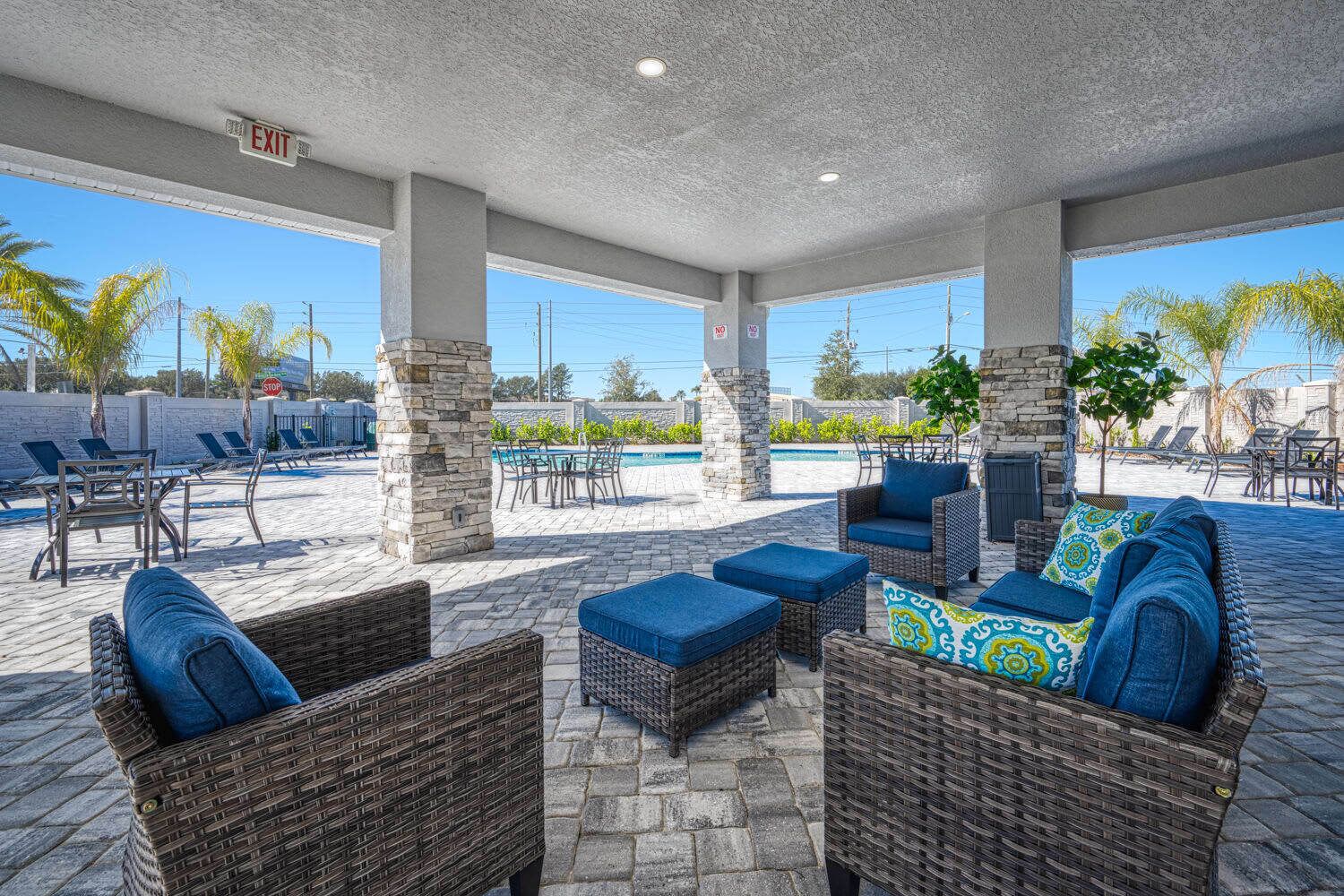 A covered outdoor seating area with wicker furniture and a pool in the background.
