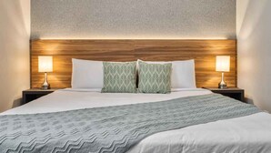 A neatly made bed with a patterned bedspread, two pillows, and two bedside lamps on wooden nightstands. - Spacious villa with themed bedrooms and private pool (Kissimmee)