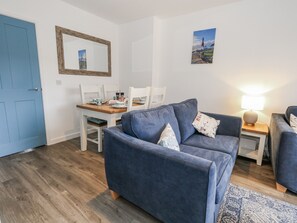 A modern living room with a blue sofa, a dining table, and a lamp. - Park View (Weymouth)