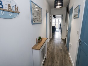 A hallway with wooden flooring, a radiator, and a wall-mounted sign reading "BEACH". - Park View (Weymouth)