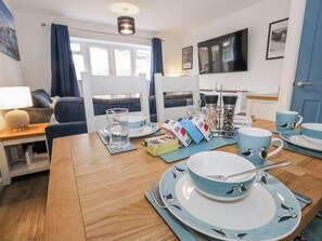 A dining area with a wooden table set for two, featuring a blue and white tableware set with penguin designs. - Park View (Weymouth)
