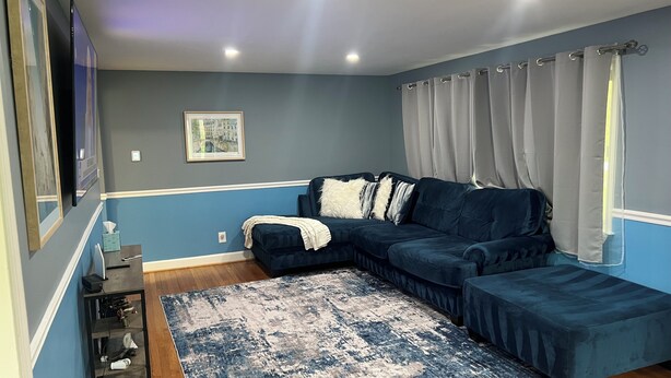 A modern living room with a dark blue sectional sofa, a patterned rug, and a framed picture on the wall. - Family friendly Home, 3BR, Old Town, Nat. Harbor & DC. Nice neighborhood (Alexandria)