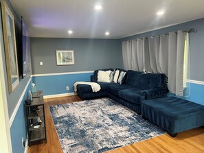 A modern living room with a dark blue sectional sofa, a patterned rug, and a framed picture on the wall. - Family friendly Home, 3BR, Old Town, Nat. Harbor & DC. Nice neighborhood (Alexandria)