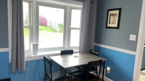 A dining area with a table and chairs, a window with curtains, a framed picture on the wall, and a power outlet. - Family friendly Home, 3BR, Old Town, Nat. Harbor & DC. Nice neighborhood (Alexandria)